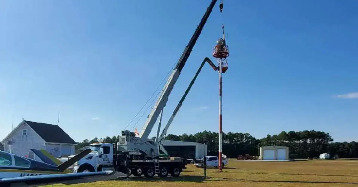 Crane lifting a prefabricated shed over a fence into a Kill Devil Hills backyard