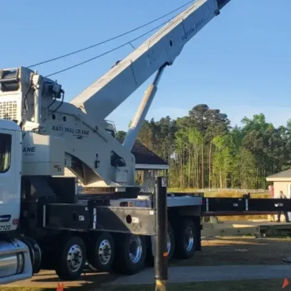 Rough terrain crane lifting steel beams on muddy ground